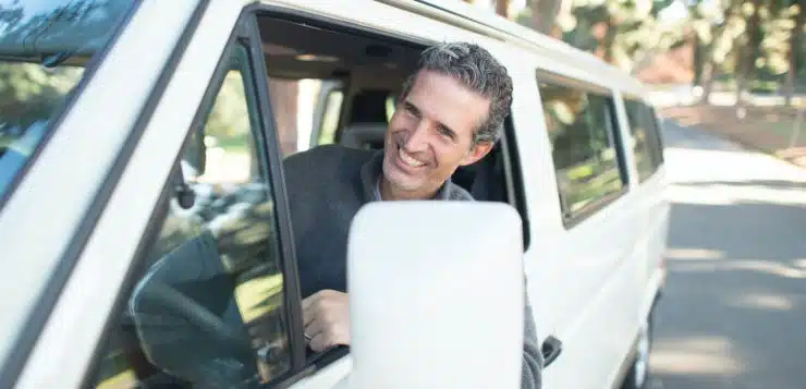 man in gray sweater leaning on van window