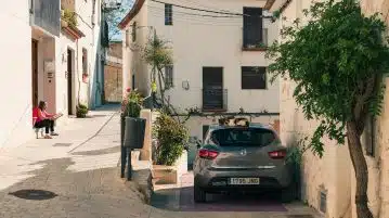 black sedan parked beside white concrete building during daytime