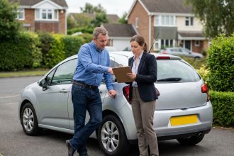 Homme d'âge moyen discutant avec un expert automobile devant sa voiture