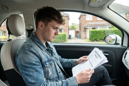 Jeune homme pensive avec documents d'assurance auto