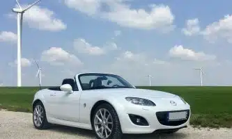white porsche 911 on green grass field under blue sky during daytime