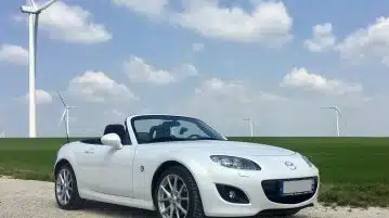 white porsche 911 on green grass field under blue sky during daytime