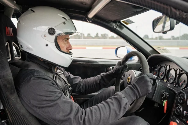 Pilote en combinaison de course au volant d'une voiture de sport lors d'un stage de pilotage sur circuit