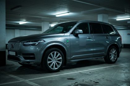 SUV hybride rechargeable garé dans un parking urbain, vue trois quarts avant montrant le badge hybride et la prise de charge